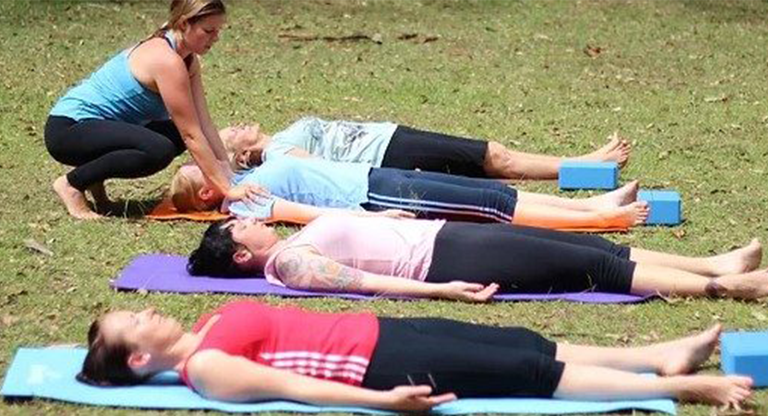 People lying down doing yoga in the park