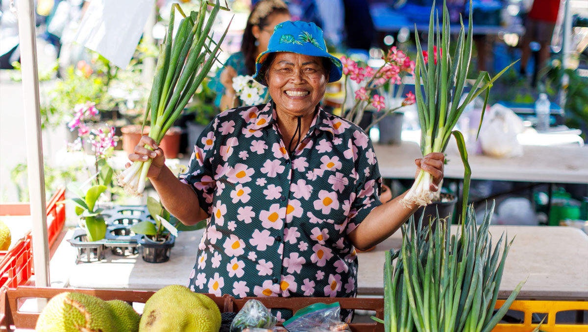 a market stall holder holding her products and smiling