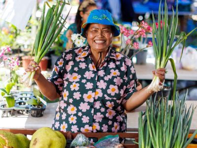a market stall holder holding her products and smiling